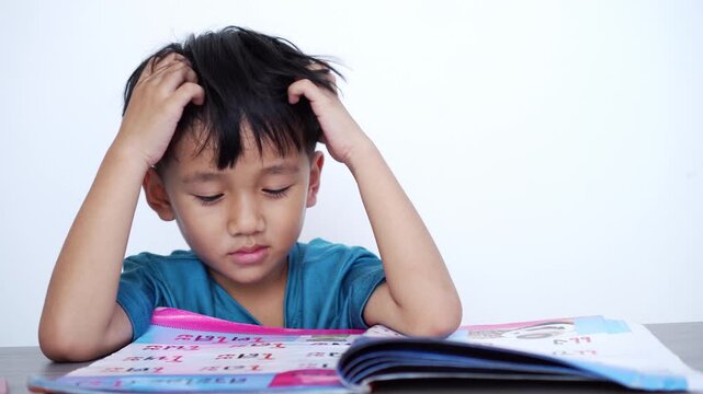 Stressed Asian boy scratching head while doing homework. Concept of academic pressure, learning difficulties, childhood stress, ADHD symptoms, and educational struggle in elementary school kids.