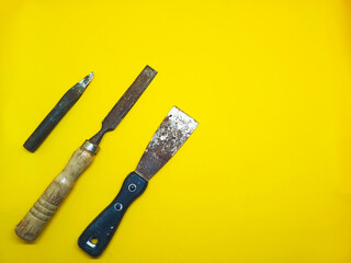 Assorted chisels and tools displayed on a bright yellow surface viewed from directly above