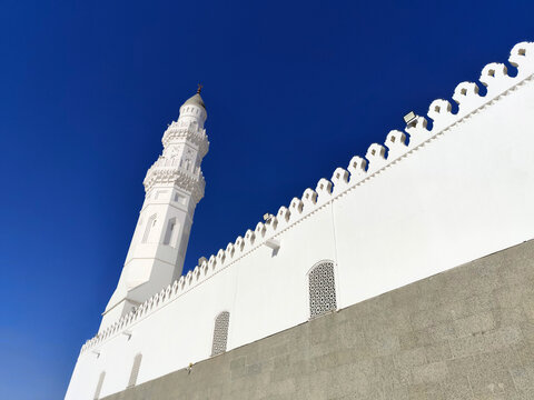 Low angle view of the iconic white minarets of Masjid Quba in Medina, Saudi Arabia, known as one of the oldest mosques in Islam, captured under a clear blue sky dur