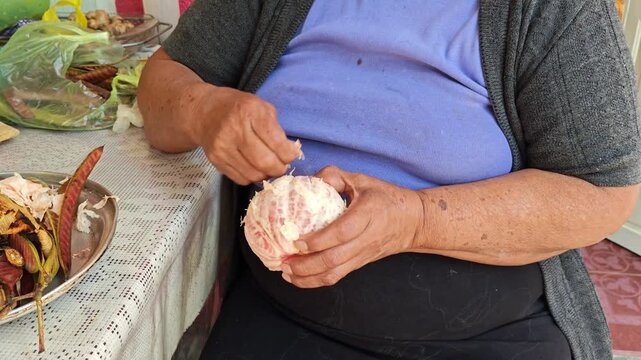 Close up of hands peeling and cleaning a red grapefruit