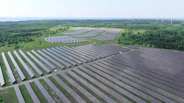 Aerial drone footage of wind turbines and solar panels at a renewable energy plant in a natural landscape near Paldiski, Estonia.