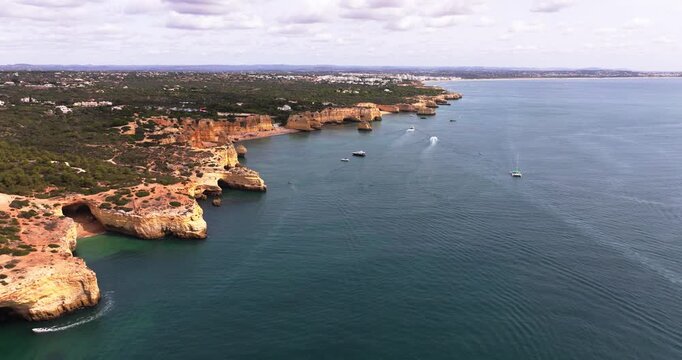 Aerial view of Benagil sea caves and Algarve coastline with boats below