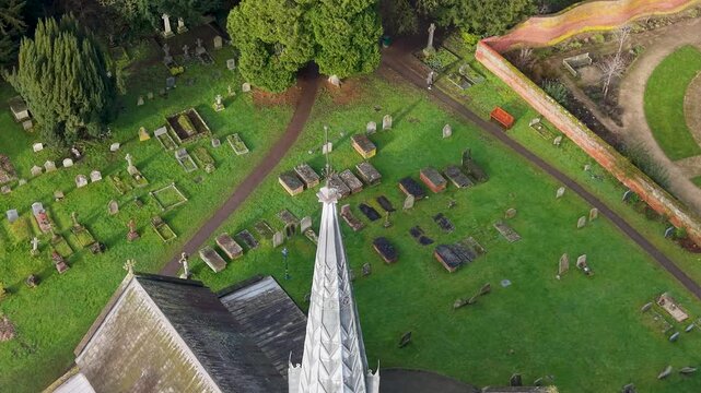 Drone orbits St Helens Church spire and cross above cemetery and graves