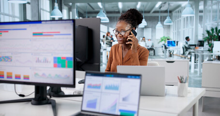 Obraz na płótnie Canvas Smiling African Businesswomen Talking To Clients On Phone