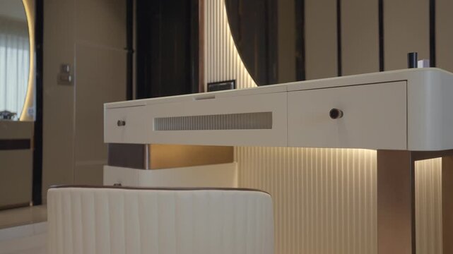 White vanity table with metallic legs, ribbed backdrop, warm underlighting, and round mirror