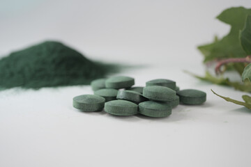 Spirulina tablets and powder on white background