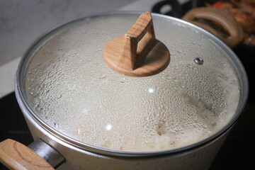 Cooking rice in a pot with a glass lid on a stovetop