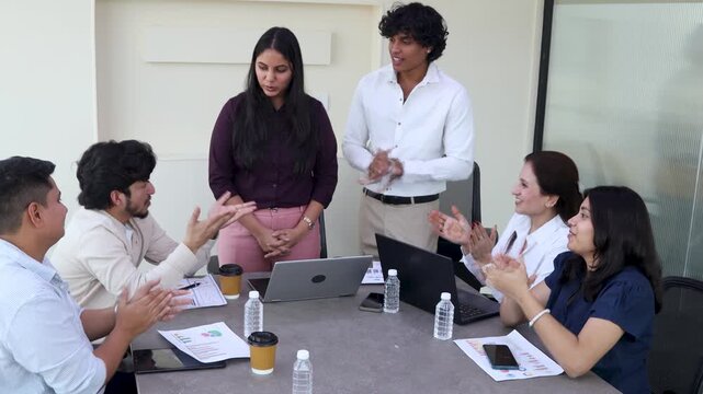 Young indian business professionals applauding colleague after successful presentation or achievement. Celebrating teamwork and shared success during a meeting in a startup office. 4k