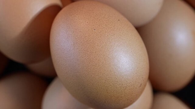 Closeup rotating stack of fresh brown chicken eggs. Smooth motion highlights natural eggshell texture, freshness, and organic food concept