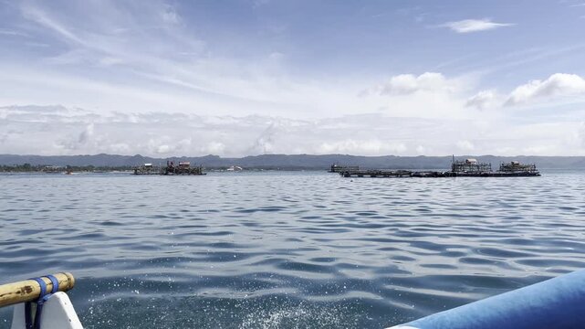 A wide shot from a moving boat captures traditional Indonesian fishing platforms, locally known as bagan or bagang, floating in the open ocean