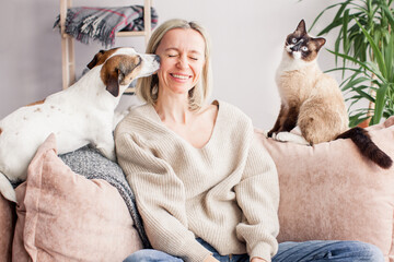 Happy woman playing with her dog on the couch at home