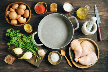 Raw ingredients for cooking chicken with mushrooms and vegetables on wooden table