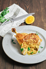 Crispy chicken leg served on a plate with herbs and lemon