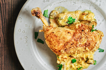 Chicken dish served on a plate with herbs and a creamy sauce at a dining table