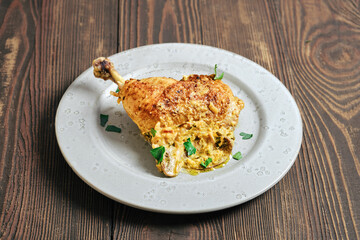 Cooked chicken leg served on a plate with creamy sauce and herbs during a meal preparation time