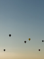 Fototapeta premium A hot air balloon flies over the city Yerevan, background of the blue sky. Aerial view of many colorful hot air balloons fly in the sky. High quality