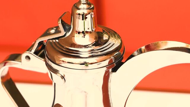 Close up of traditional arabic chrome coffee pot with elongated curved spout. Historical metal cookware design reflecting middle eastern culture heritage craftsmanship and classic coffee traditions.
