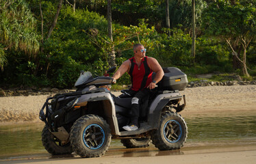 Fototapeta premium A man engages in extreme ATV riding on sand beach early in the morning
