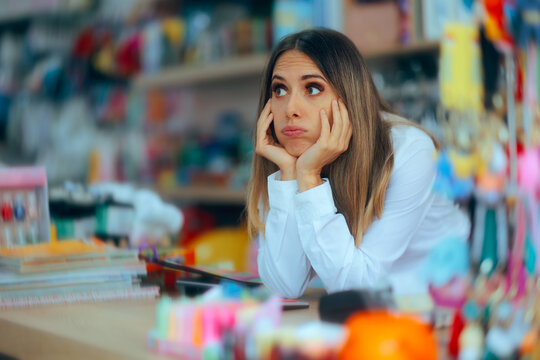 Sad Tired Saleswoman in a Store Waiting for Customers. Demotivated store employee waiting for business in an empty shop during a sales slump 
