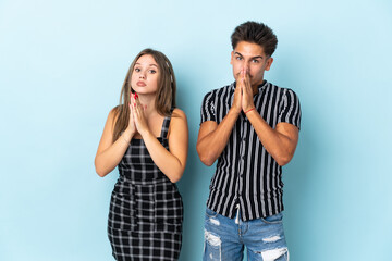Naklejka premium Teenager caucasian couple isolated on blue background keeps palm together. Person asks for something