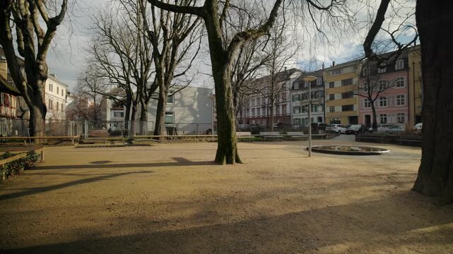 Panning shot of a public park in Basel, Switzerland, showing green lawn, trees, and urban nature on a bright day.