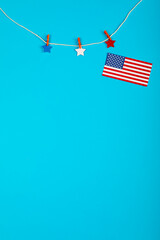 Obraz premium Stars-decorated clothespin and loose USA flag on string against a blue backdrop with space