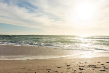 Naklejka premium Scenic view of waves on shore at beach against sky during sunny day