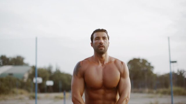 Man lifts kettlebell in outdoor training session at a park in the late afternoon