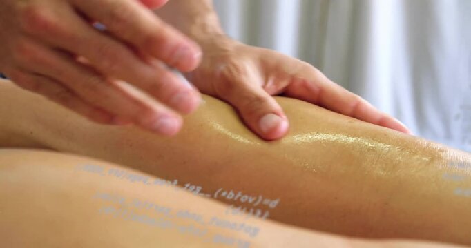 Therapist hands entering TL spreading oil kneading legs on massage table, code over skin for relief