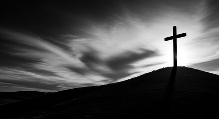 Dramatic black and white silhouette of the crucifixion cross stands on a hill under a somber, cloudy good friday sky. © ryoga