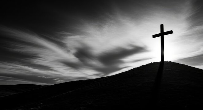 Dramatic black and white silhouette of the crucifixion cross stands on a hill under a somber, cloudy good friday sky.
