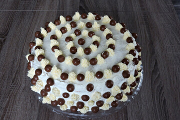 A minimalist homemade white birthday cake with chocolate balls and buttercream peaks