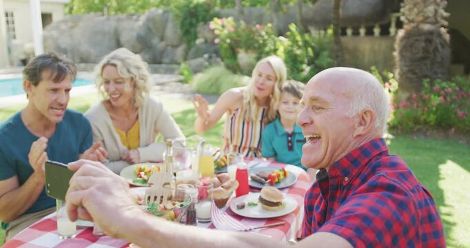 Happy caucasian family having dinner and taking selfie in garden