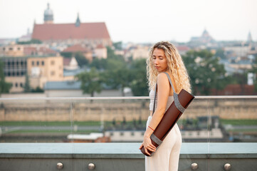 Naklejka premium Woman With Yoga Mat On Rooftop