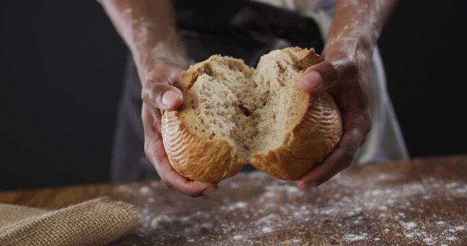 Video of cook holding loaf of bread on black background