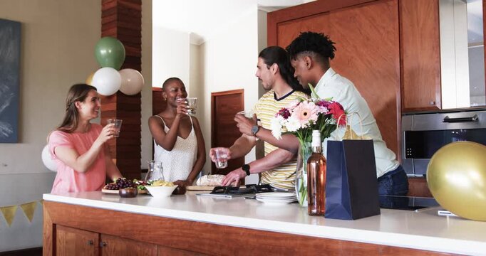 Celebrating in kitchen, friends having drinks and snacks, sharing joyful conversation