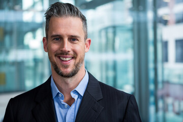 Fototapeta premium Man smiling at camera in modern office lobby, wearing pinstripe suit jacket and light blue shirt