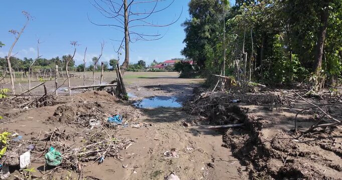 Polluted dry riverbed with trash and debris.