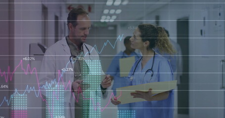 Image of graphs, changing numbers over caucasian doctor standing and discussing patient reports © vectorfusionart