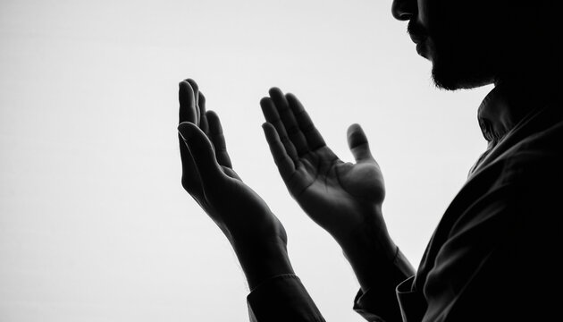 Silhouette of an individual with hands raised in earnest prayer, embodying deep spirituality and heartfelt devotion in a moment of quiet contemplation and introspection