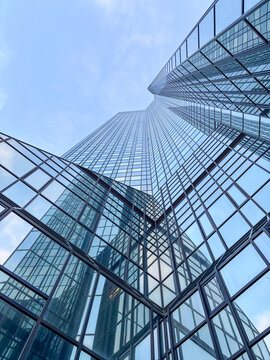 Glass skyscraper with reflections under blue sky.