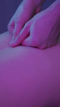 Massage in clinic - a man therapist massaging bare back of a female client