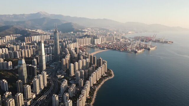 Coastal city skyline with port and mountains at sunset