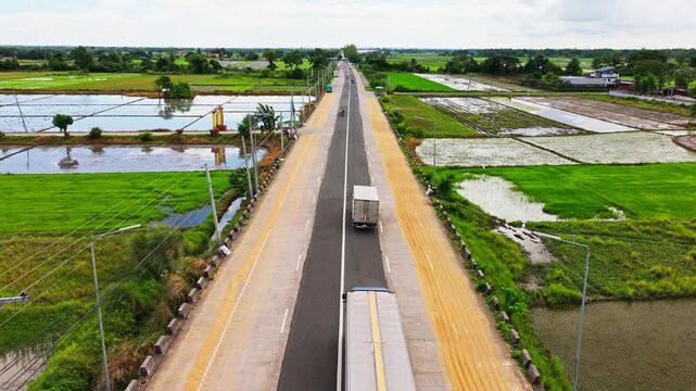 Aerial view of vehicles on Romulo Highway beside rice grains drying in sun