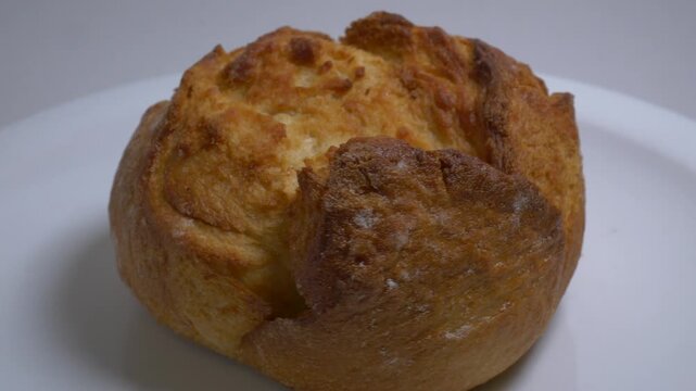 fresh, crusty bread rolls rotate slowly on a white plate in a studio, highlighting their golden-brown texture and artisanal appearance in a close-up shot.