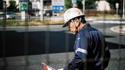 Experienced Japanese construction worker in helmet at urban work site