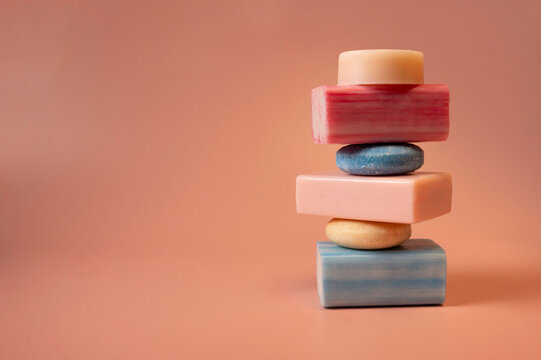 Stacked soap and shampoo bars arranged in a minimalist composition on a pastel background. The image emphasizes texture and soft colors, suitable for skincare, haircare, wellness, and clean design