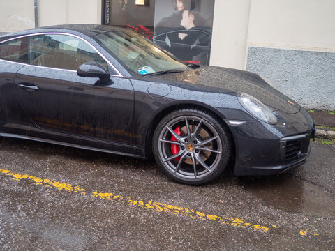 Porsche 911 Carrera sports car parked in rain, showing luxury model details and aerodynamic design