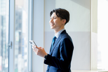 Fototapeta premium オフィスでスマホを持つビジネスマン