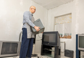 Man tv repairman holding old television for diagnosis of problem. Individual entrepreneur working on electronic device in small business